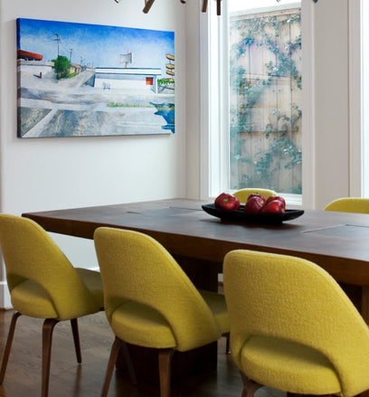 A mid century modern landscape painting decorates a light-filled dining room