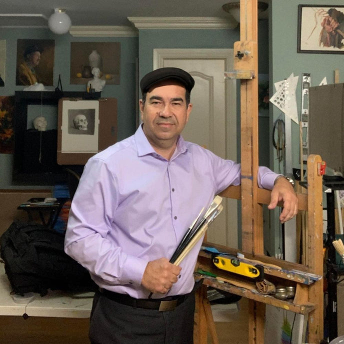  UGallery artist Andres Lopez beside an easel, holding paintbrushes 