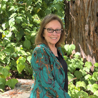  UGallery artist Catherine McCargar standing in front of a tree and greenery 