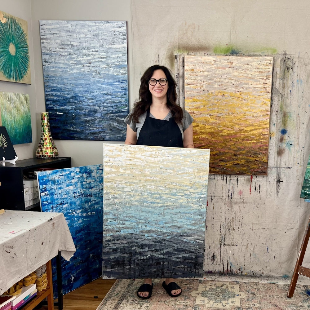  UGallery artist Janet Hamilton holding one of her abstract paintings 