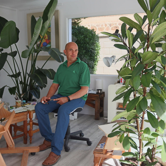  UGallery artist Javier Ortas sitting in his plant-filled studio 