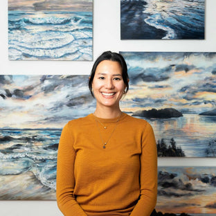  UGallery artist Tiffany Blaise in front of a gallery wall with her seascape paintings 