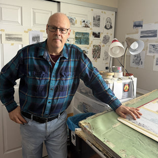  UGallery artist Vic Roschkov leaning on a worktable in his studio 