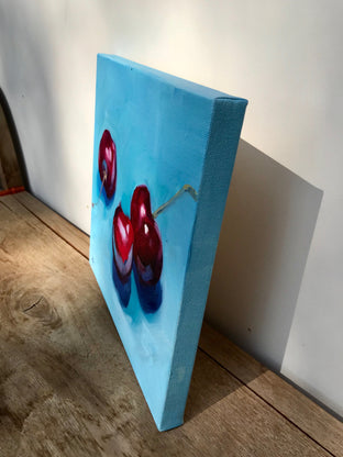 Original art for sale at UGallery.com | Three Cherries on Blue by Malia Pettit | $275 | oil painting | 10' h x 10' w | photo 2
